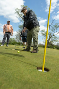 Man on the putting green with golf hole